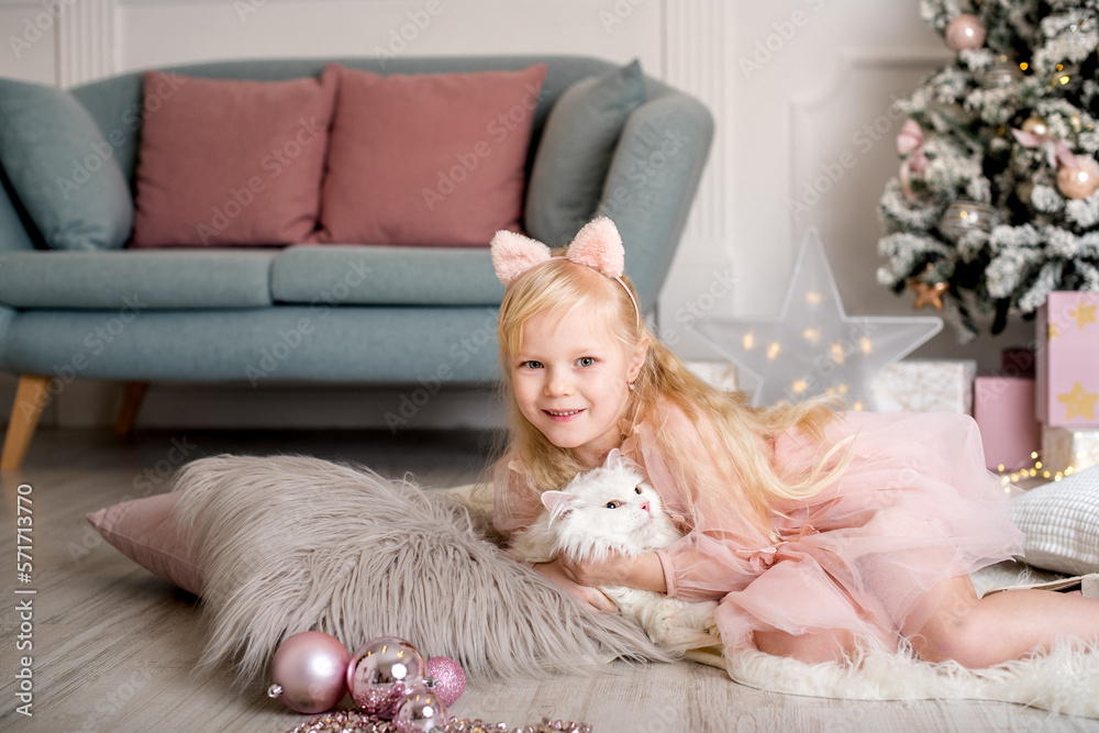 Φωτογραφία a young girl in a pink dress and her fluffy white cat enjoying the holiday spirit by a Christmas tree