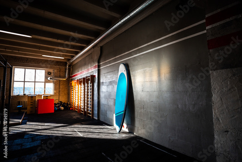 Blue inflatable stand-up paddle board SUP by the wall. Surfing and sup boarding equipment close up photo