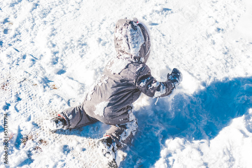 Dziecko ubrane w kombinezon zimowy, bawiące się w śniegu. © Miosz