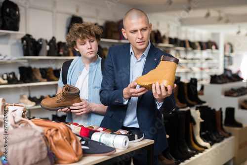 Portrait of man and teenage boy shopping for mens shoes in store, choosing demi-season lace up boots.
