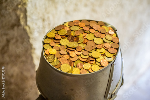 donate collection made of metal with lots of small european coins in it