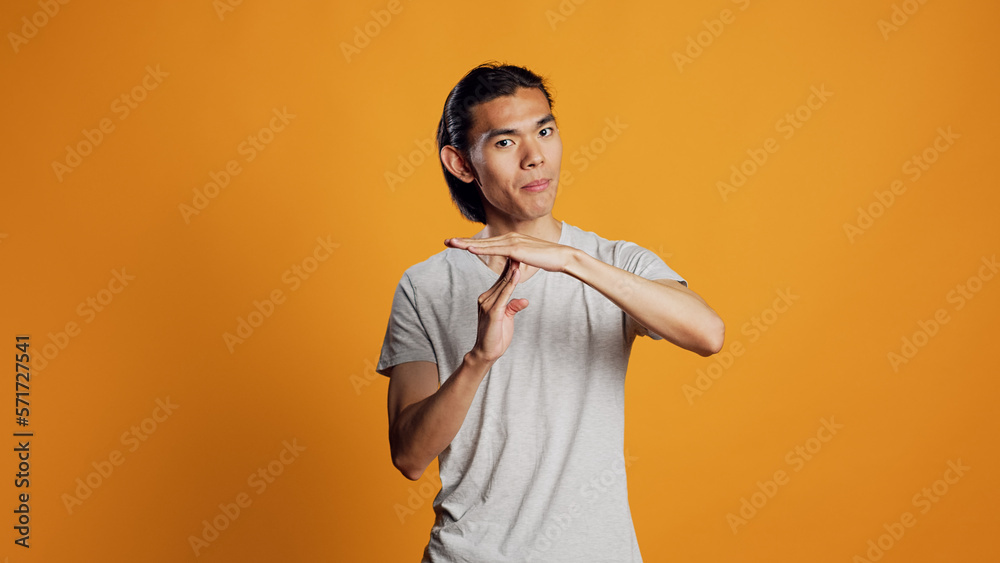 Young adult doing t shape symbol on camera, showing break or pause sign for denial and refusal. Asian casual guy expressing rejection and asking for half time, body language concept. Young adult doing t shape symbol on camera, showing break or pause sign for denial and refusal. Asian casual guy expressing rejection and asking for half time, body language concept.