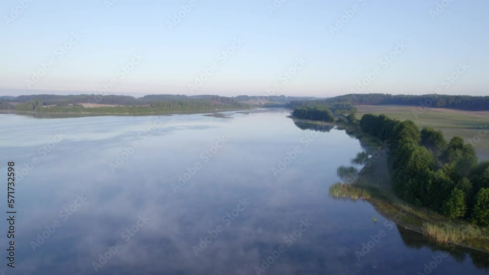 Foggy morning on a beautiful lake surrounded by forests and fields. A small village located near a lake in fog and morning sun. Foggy morning on a beautiful lake surrounded by forests and fields. A small village located near a lake in fog and morning sun.