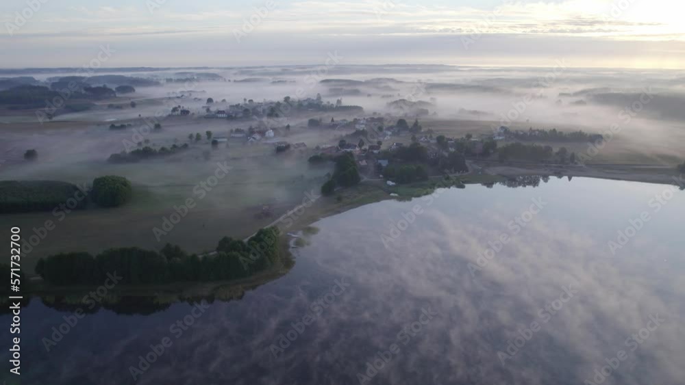 Foggy morning on a beautiful lake surrounded by forests and fields. A small village located near a lake in fog and morning sun. Foggy morning on a beautiful lake surrounded by forests and fields. A small village located near a lake in fog and morning sun.