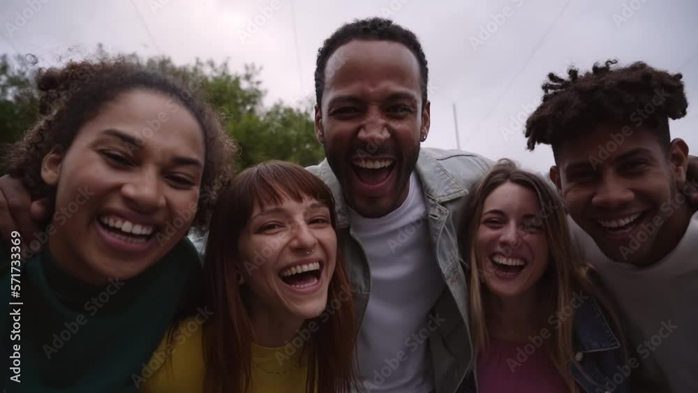 Young people approaching and leaning towards camera smiling. Happy friendship cheerful group together outdoors. Smiling students on a trip. Multi-ethnic colleagues hugging each other in the city. Young people approaching and leaning towards camera smiling. Happy friendship cheerful group together outdoors. Smiling students on a trip. Multi-ethnic colleagues hugging each other in the city.