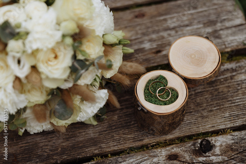 A box for wedding rings made of wood with floral decor lies on a wooden surface. Wedding accessories.