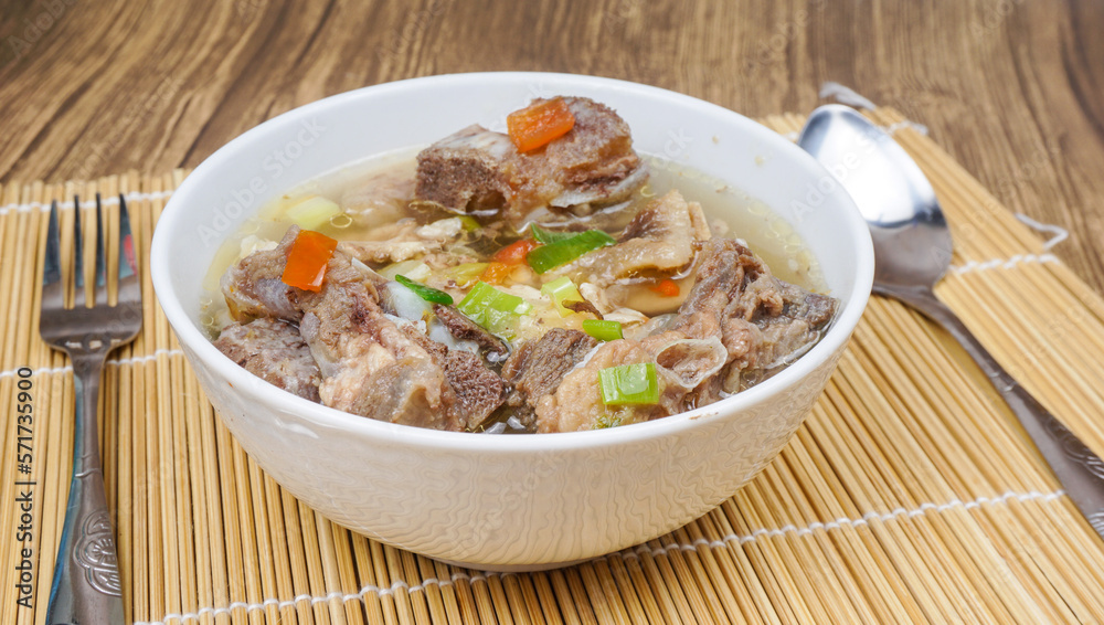 Sop Iga (Beef ribs soup) is Indonesian soup. served in white bowl. selective focus Sop Iga (Beef ribs soup) is Indonesian soup. served in white bowl. selective focus