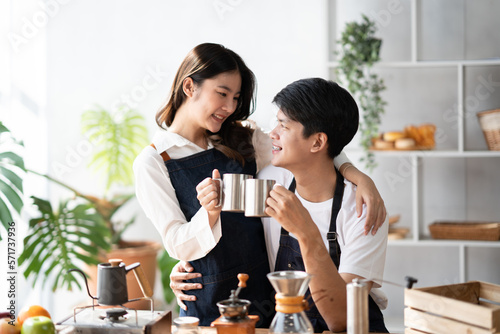 Young smiling couple in love spending a weekend morning together while making coffee at the kitchen, having breakfast together.