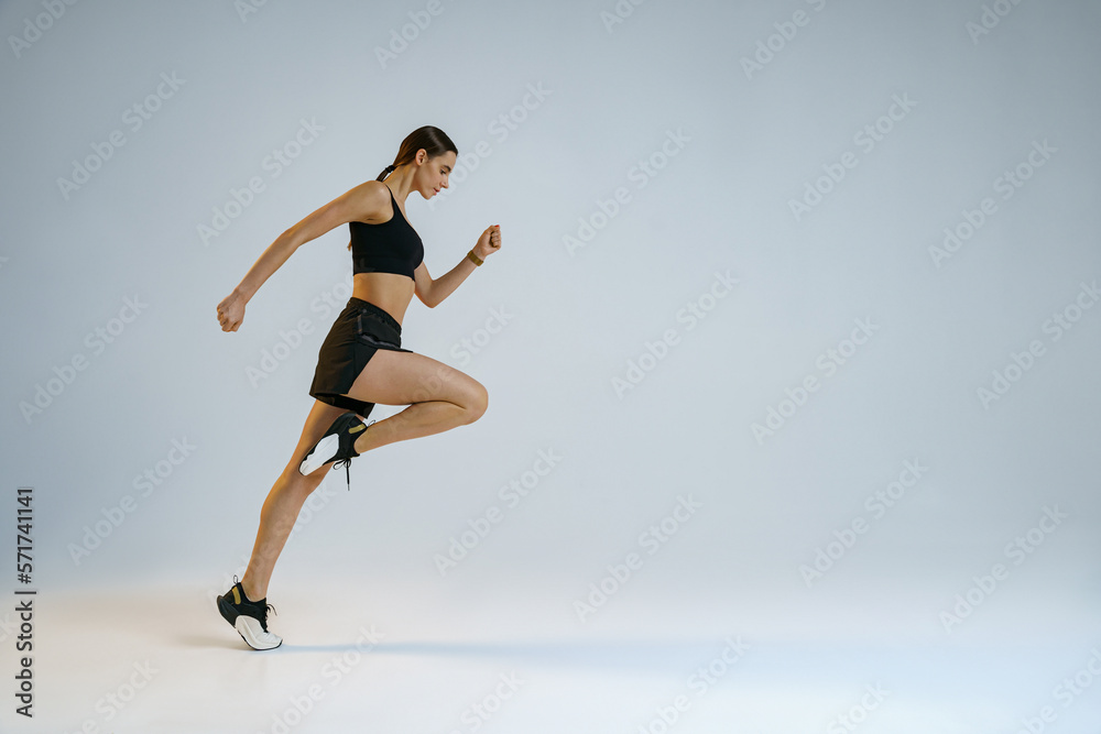 Athletic active woman running on studio background. Dynamic movement