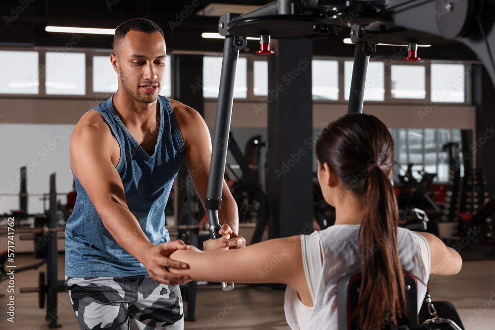 Young woman working out with professional trainer in modern gym Young woman working out with professional trainer in modern gym