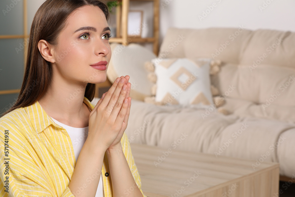 Woman with clasped hands praying at home, space for text Woman with clasped hands praying at home, space for text