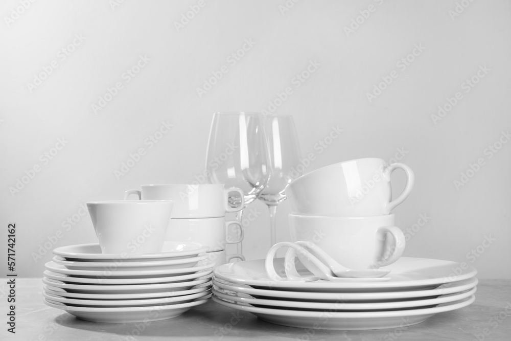 Fototapeta premium Set of clean dishware and glasses on grey table against light background