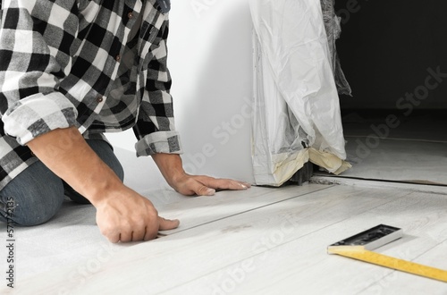 Professional worker installing new laminate flooring indoors, closeup