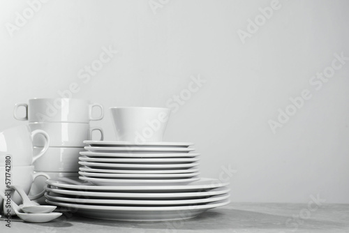 Set of clean dishware on grey table against light background. Space for text