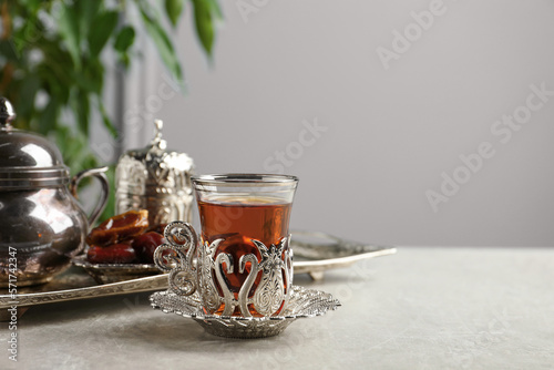 Slika na platnu Tea and date fruits served in vintage tea set on grey table, space for text
