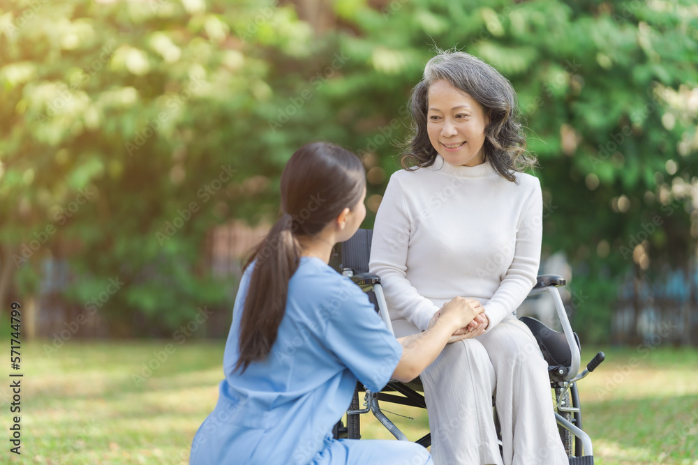 Young asian care helper with asia elderly woman on wheelchair relax together park outdoors to help and encourage and rest your mind with green nature. Young asian care helper with asia elderly woman on wheelchair relax together park outdoors to help and encourage and rest your mind with green nature.