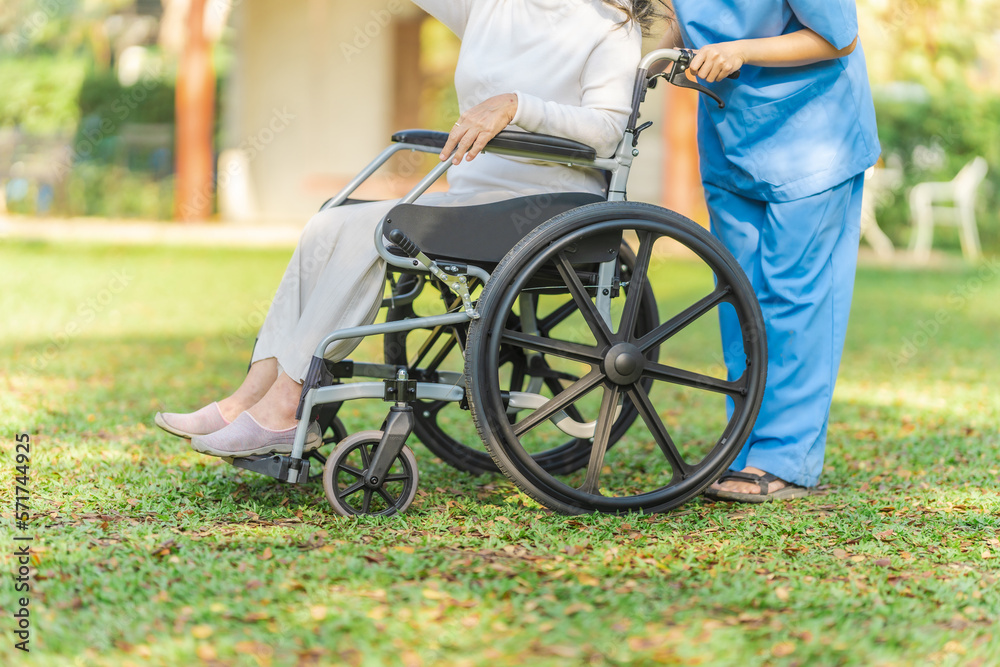 Obraz premium Young asian care helper with asia elderly woman on wheelchair relax together park outdoors to help and encourage and rest your mind with green nature.