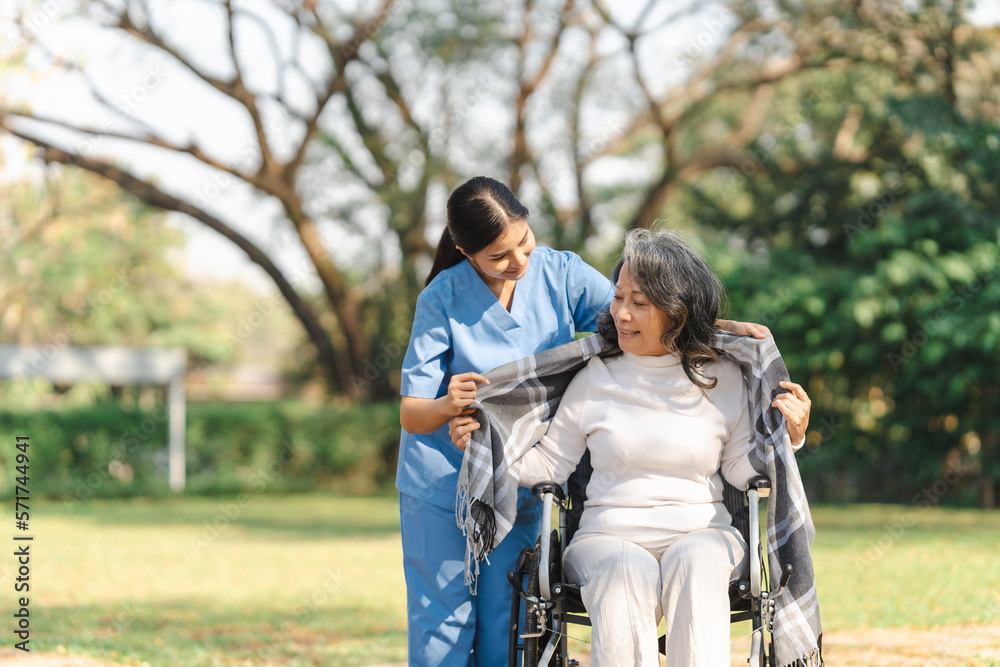 Young asian care helper with asia elderly woman on wheelchair relax together park outdoors to help and encourage and rest your mind with green nature. Young asian care helper with asia elderly woman on wheelchair relax together park outdoors to help and encourage and rest your mind with green nature.