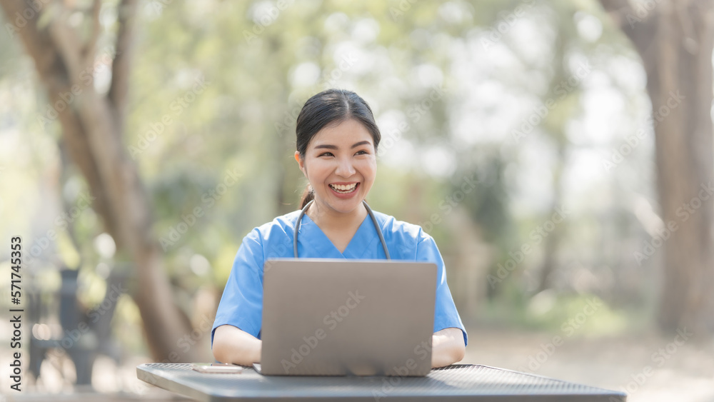 Asian female nurse working outdoor video call with patient online on laptop at desk in park. Asian female nurse working outdoor video call with patient online on laptop at desk in park.
