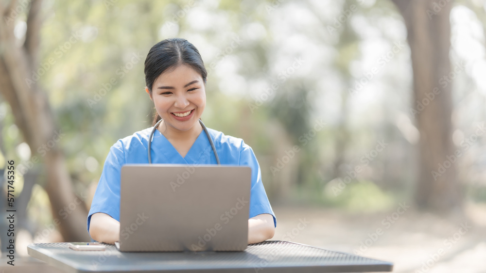 Asian female nurse working outdoor video call with patient online on laptop at desk in park. Asian female nurse working outdoor video call with patient online on laptop at desk in park.