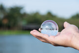 Crystal globe in male hand and on river background.