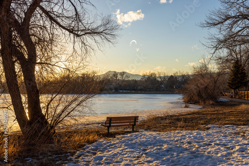 Kendrick Lake Park in Denver, Colorado. Iced lake at sunset with a bench on the shore photo