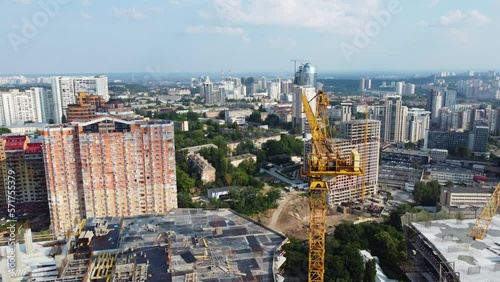 Drone aerial above Kyiv city. Panning around construction cranes surrounded by tall apartment buildings during a sunny summer day. Ukraine urban landscape 4k