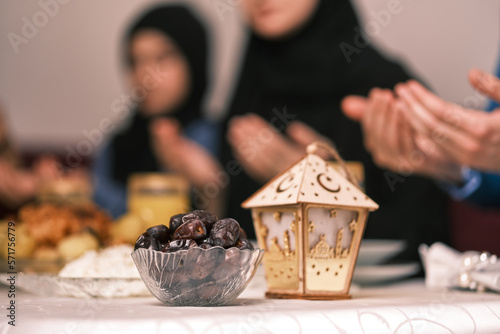 Photography Happy Muslim family together making iftar dua to break fasting during Ramadan at the dining table at home focus on a bowl of dates