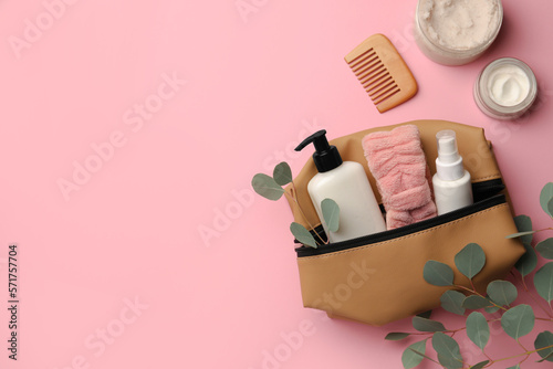 Preparation for spa. Compact toiletry bag with different cosmetic products, comb and eucalyptus on pink background, flat lay. Space for text