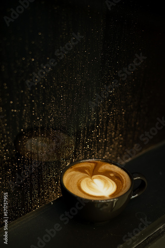 A Hot Coffee Latte with Artistic Heart Shape on a Black Table at a Coffee Shop.