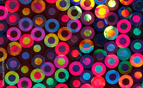 Vibrant, multi colored abstract background created by taking a macro photograph of the minuscule overlapping circles on the reverse side of metallic wrapping paper as they refract the sunlight.