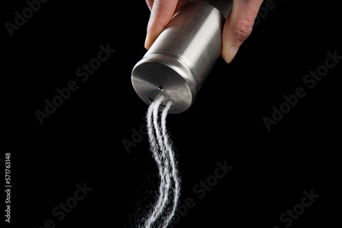 The salt spilled from the salt shaker on black background. photo