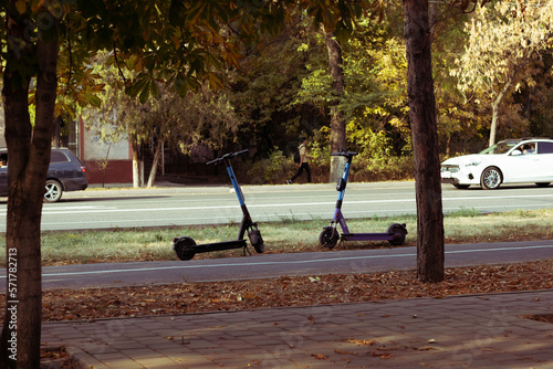 two electric scooters stand on the sidewalk without people - horizontal city photo