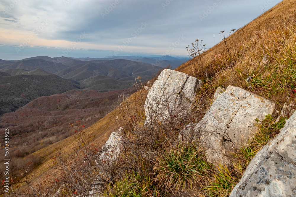 Large stones on the slope of a high mountain. Panoramic view of the Caucasus mountains. Mountain landscape with beautiful Caucasian nature. View of the mountain range under a cloudy sky. 