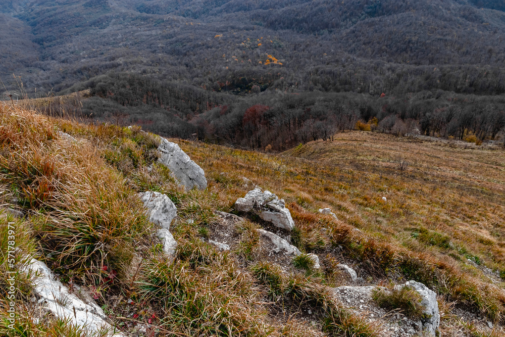 Large stones on the slope of a high mountain. Panoramic view of the Caucasus mountains. View of the mountain range under a cloudy sky. Mountain landscape with beautiful Caucasian nature. 
