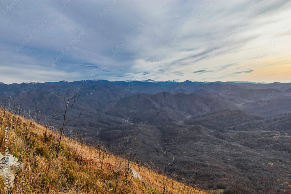Mountain landscape with beautiful Caucasian nature. Landscape of a mountain range on an autumn morning. Panoramic view of the Caucasus mountains. View of the mountain range under a cloudy sky.  