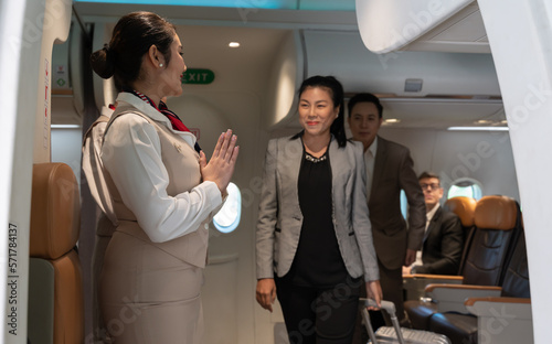Air hostess or flight attendant standing at airplane entrance door and greeting passengers leaving airplane cabin