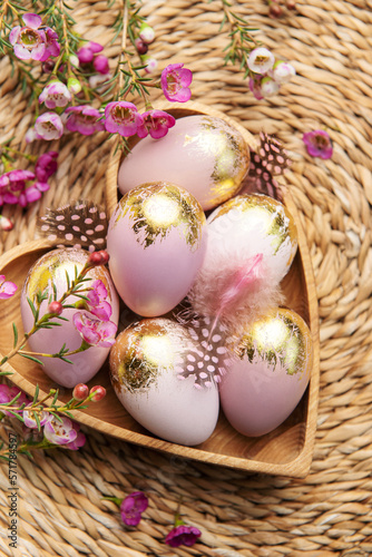 Easter decor. Easter eggs painted in gold in a heart-shaped wooden bowl.