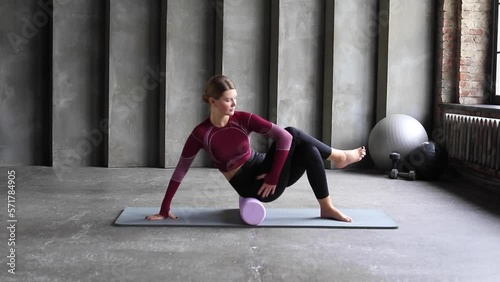 A young woman performs a myofascial hip massage with a roller. Muscle recovery