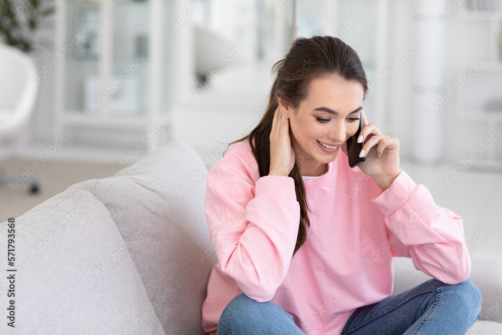 Happy woman talking on mobile phone sitting on comfortable couch Happy woman talking on mobile phone sitting on comfortable couch