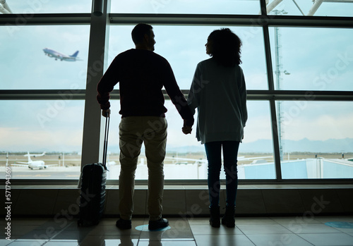 Silhouette, travel and holding hands with couple in airport for departure, flight and vacation break. Shadow, holiday and tourism with man and woman by window for journey, international and boarding