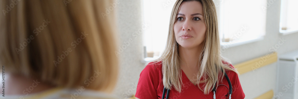 Female therapist doctor in red uniform consults and listens to patient in clinic Female therapist doctor in red uniform consults and listens to patient in clinic