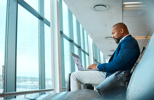 Travel, laptop and website with black man in airport for online booking, vip lounge and communication. Relax, internet and technology with businessman reading on layover for vacation, trip and flight photo