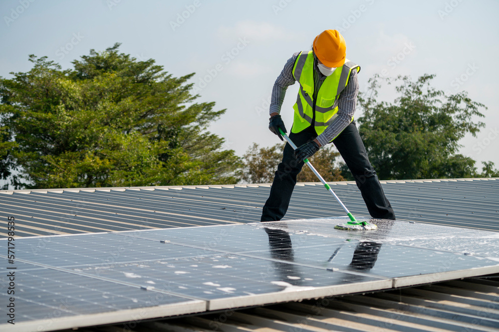 Maintenance technician using high pressure water to clean the solar panels that are dirty with dust to improve the efficiency of solar energy storage.