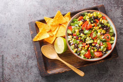 Cowboy caviar or Texas salad made with beans, corn, bell peppers, and tomato in chili lime vinaigrette for a delicious party appetizer closeup in the bowl on the table. Horizontal top view from above