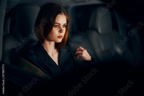 a close horizontal portrait of a stylish, luxurious woman in a leather coat sitting in a black car at night in the passenger seat © SHOTPRIME STUDIO