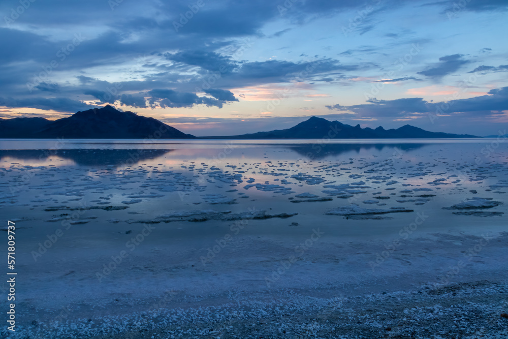 Scenic view of beautiful mountains reflecting in lake of Bonneville Salt Flats at sunset, Wendover, Western Utah, USA, America. Looking at summits of Silver Island Mountain range. Romantic atmosphere