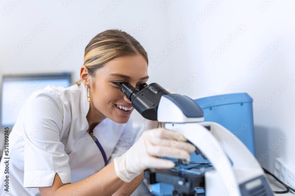 Medical Science Laboratory: Beautiful Scientist Looking Under Microscope Does Analysis of Test Sample. Young Specialists, Using Advanced Technology Equipment Medical Science Laboratory: Beautiful Scientist Looking Under Microscope Does Analysis of Test Sample. Young Specialists, Using Advanced Technology Equipment