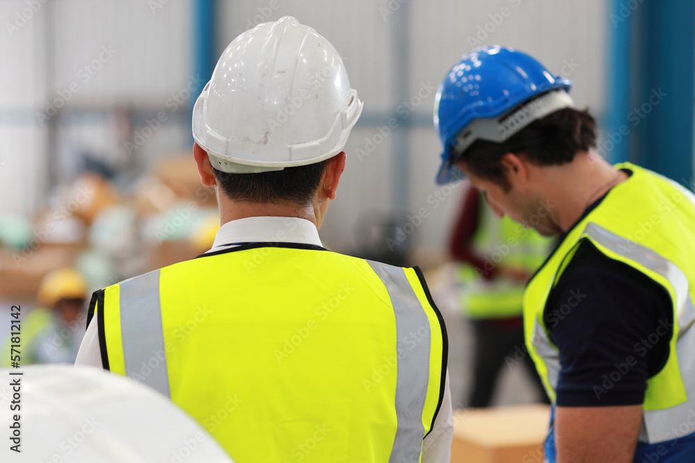 Rear view architect or engineering men and worker standing and checking large warehouse with tablet. Multiethnic two business manager controlling work at warehouse industry building. Rear view architect or engineering men and worker standing and checking large warehouse with tablet. Multiethnic two business manager controlling work at warehouse industry building.