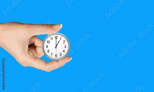 Classic clock in a human's hand on color background